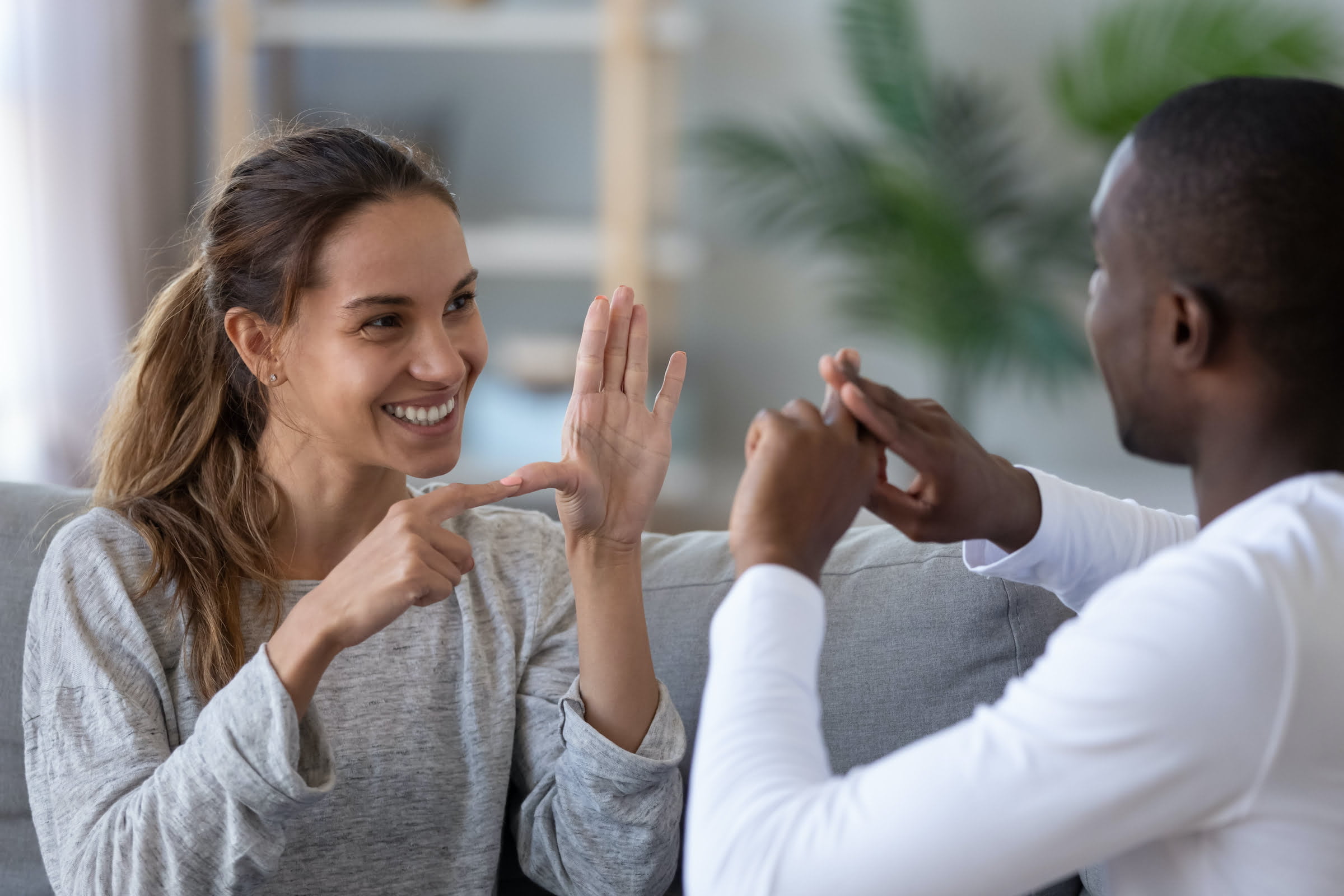 peer support A young white woman and a young black man sit facing each other using American sign language.