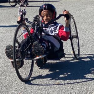 young african american boy riding a handcycle