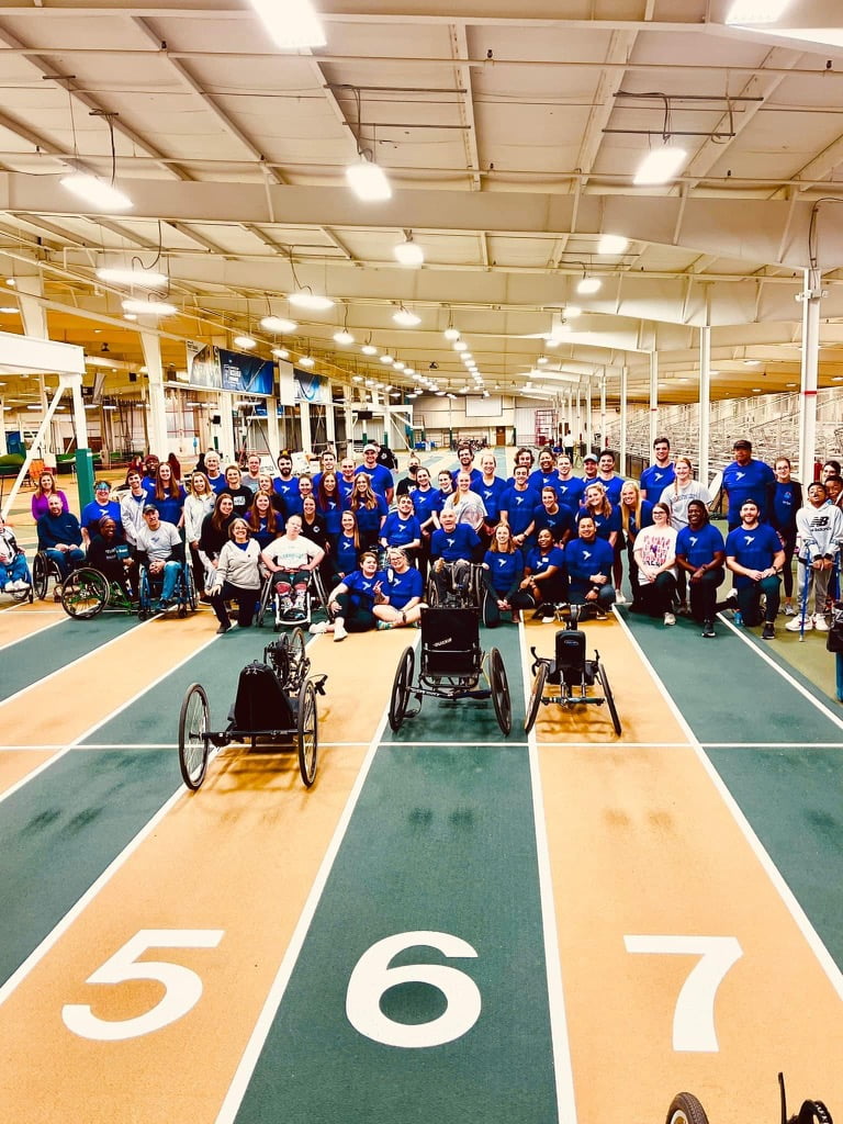 group of approximately 40 people of varying abilities on an indoor tracking